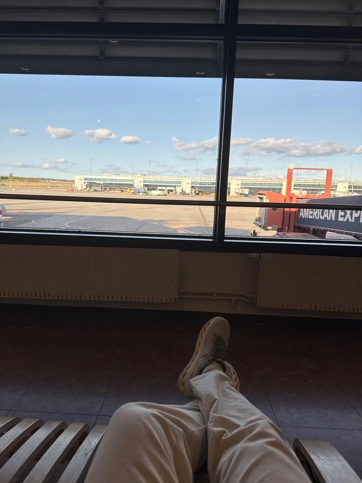 Feet up in an airport lounge, planes outside the window