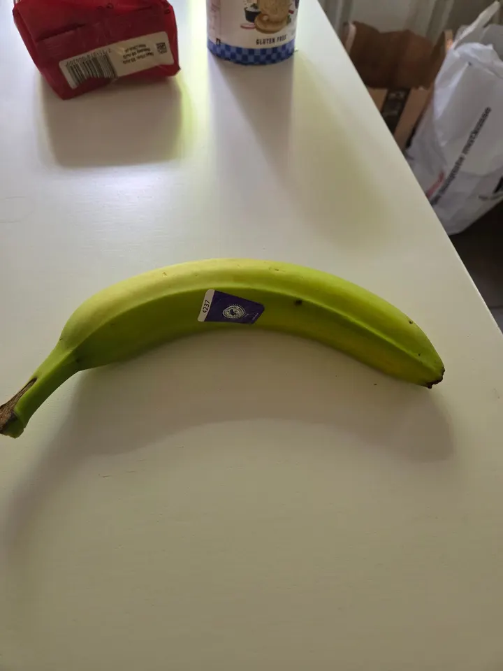 A single green banana on a kitchen table