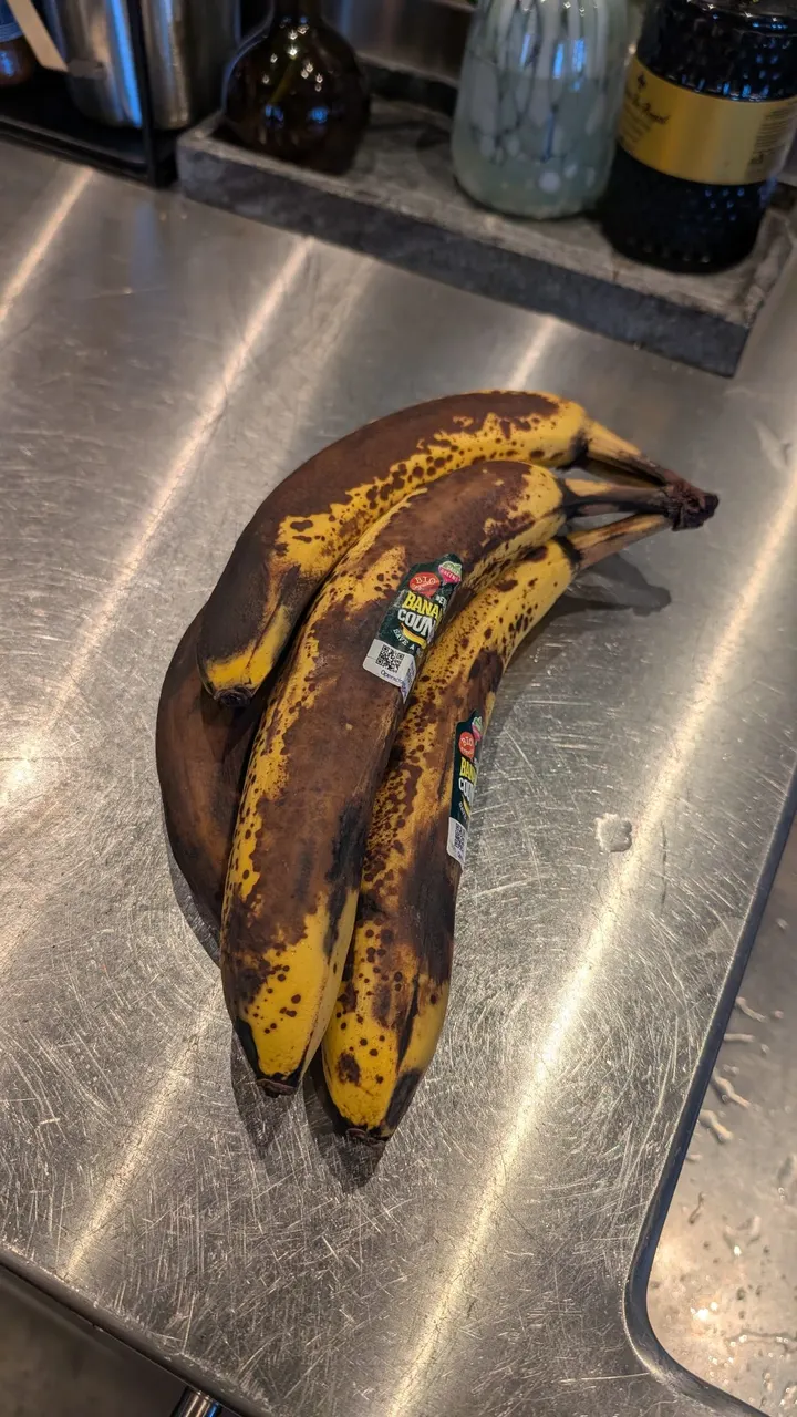 Three very ripe bananas on a steel kitchen counter